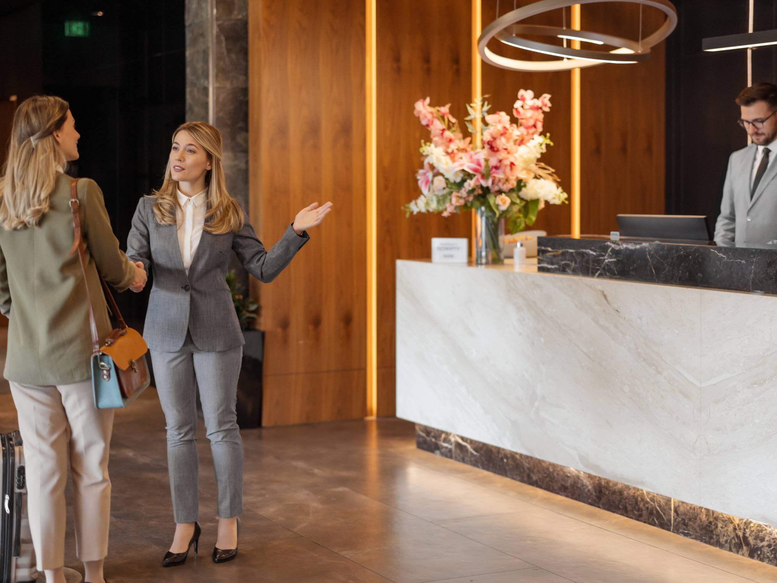 hotel reception area with hospitality business manager aiding guest skillfully on the left